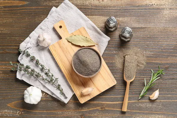 Karabiber tozu ve ahşap arka planda farklı baharatlar olan bir kase.