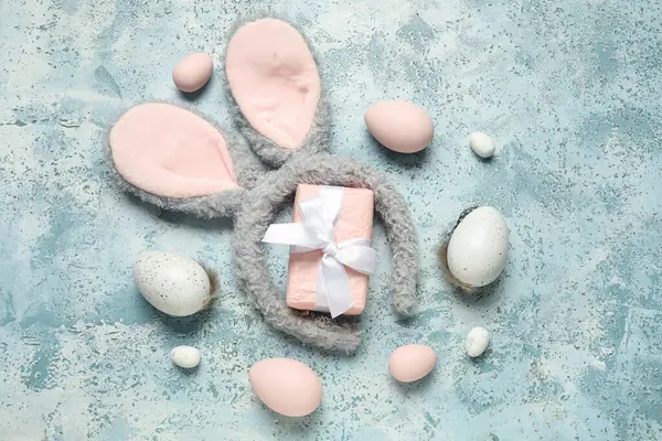 Paskalya yumurtası ve turkuaz grunge arka planında hediye kutusu olan tavşan kulaklı.