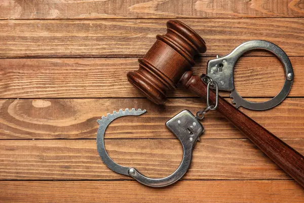 Tahta arka planda yargıç tokmağı olan kelepçeler.