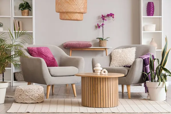 Oturma odasının içinde raflar, sehpalar ve kanepede mor yastıklar var.