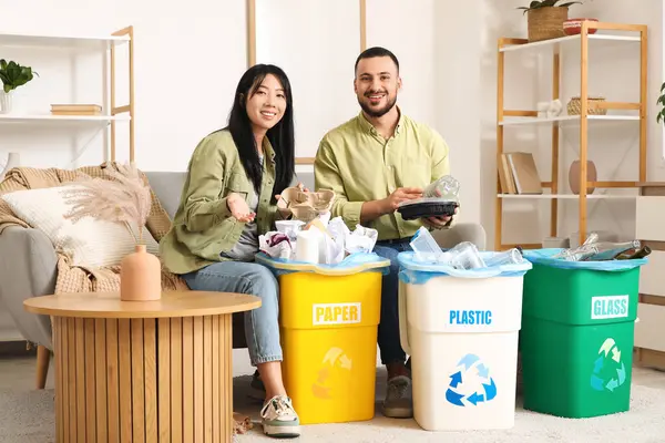 Evdeki çöp bidonlarını düzenleyen genç bir çift. Küresel Geri Dönüşüm Günü