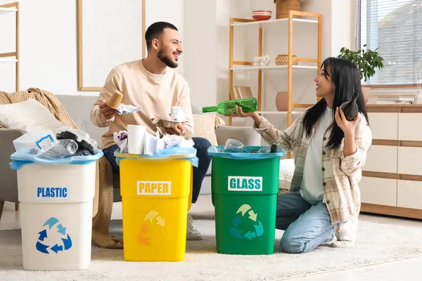 Evdeki çöp bidonlarını düzenleyen genç bir çift. Küresel Geri Dönüşüm Günü