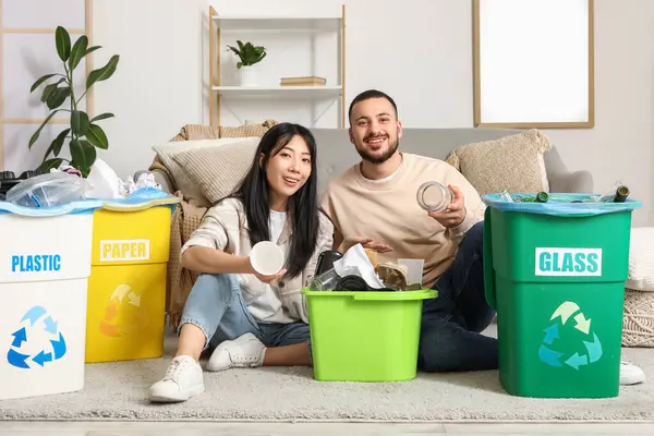 Evdeki çöp bidonlarını düzenleyen genç bir çift. Küresel Geri Dönüşüm Günü