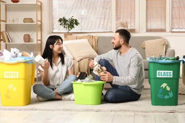 Evdeki çöp bidonlarını düzenleyen genç bir çift. Küresel Geri Dönüşüm Günü