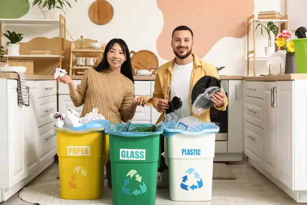 Evdeki çöp bidonlarını düzenleyen genç bir çift. Küresel Geri Dönüşüm Günü