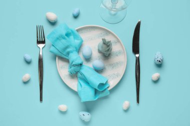 Mavi arka planda Paskalya yumurtası ve oyuncak tavşanı olan güzel bir masa.