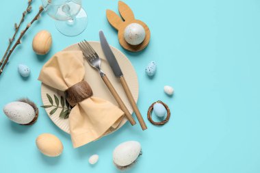 Beautiful table setting with Easter eggs and pussy willow branches on blue background