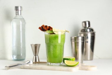 Mermer kesim tahtası, beyaz arka planda pastırma, limon ve kerevizle süslenmiş bir bardak Bloody Mary kokteyli.