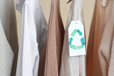 Bej arkaplanda asılı geri dönüşüm etiketli giysiler