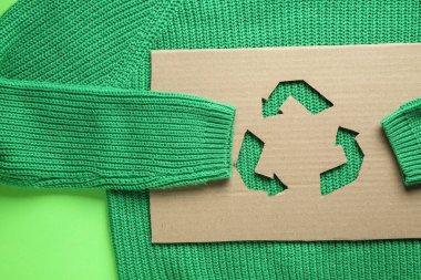 Yeşil arkaplanda geri dönüşüm işareti olan kazak