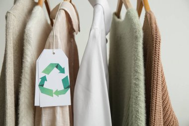 Beyaz arkaplanda asılı geri dönüşüm etiketli giysiler, yakın plan
