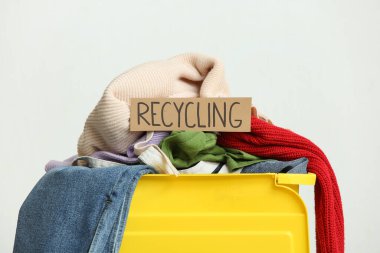 Beyaz arkaplanda giysi ve geri dönüşüm işareti olan çöp kutusu