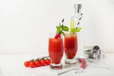 Beyaz arka planda kırmızı biberli ve kerevizli Bloody Mary kokteyli.