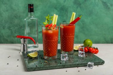 Beyaz masada kırmızı biberli, limonlu ve buzlu Bloody Mary kokteyli.