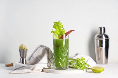 Beyaz arka planda kereviz, pastırma ve limonlu yeşil Bloody Mary kokteyli.