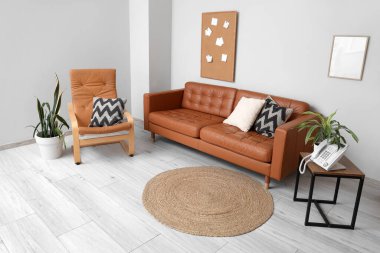 Yumuşak yastıklı ve rahat koltuklu kahverengi deri kanepe.