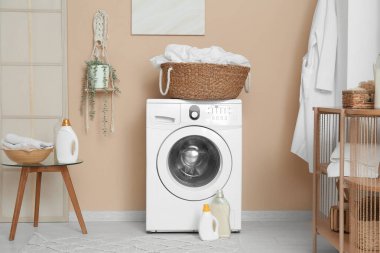 Modern çamaşır makinesi, raf ünitesi ve deterjan şişeleriyle şık bir çamaşır odası.