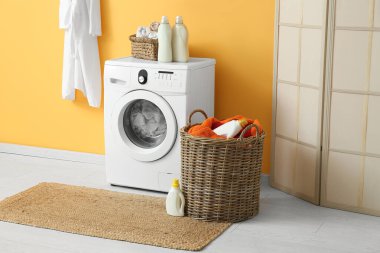 Modern çamaşır makinesi, hasır sepeti ve deterjan şişeleriyle şık bir çamaşır odası.