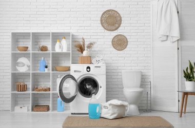 Modern çamaşır makinesi, raf ünitesi, klozet ve deterjan şişeleriyle şık bir çamaşır odası.