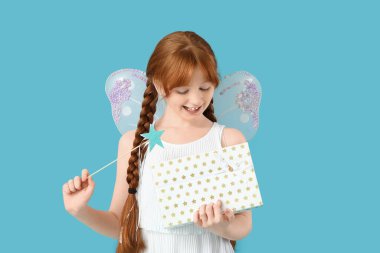 Mavi arka planda sihirli değneği ve hediye kutusu olan sevimli kızıl saçlı peri.