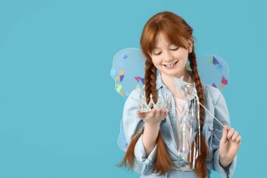 Mavi arka planda asası ve tacı olan peri kılığındaki tatlı kızıl kız.