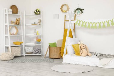 Paskalya için dekore edilmiş çocuk odasının içinde yatak ve raf üniteleri var.