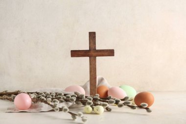 Söğüt dallarıyla ahşap haç ve beyaz grunge arka planda boyanmış yumurtalar. Paskalya kutlaması