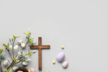 Boyanmış yumurtaları ve gri arka planda güzel çiçekleri olan ahşap haç. Paskalya kutlaması