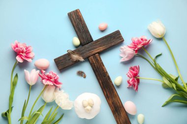 Paskalya pastalı ahşap haç, mavi arka planda boyanmış yumurta ve lale çiçekleri.