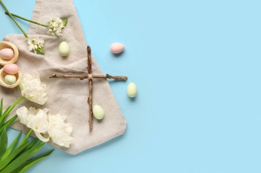 Mavi arka planda boyanmış yumurta ve çiçeklerden yapılmış haç. Paskalya kutlaması