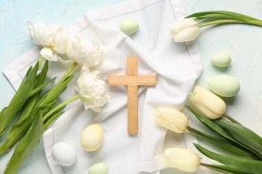 Açık mavi arka planda boyanmış yumurta ve lale çiçekli ahşap haç. Paskalya kutlaması