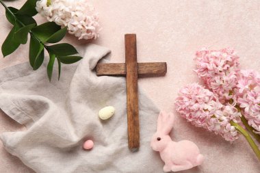 Ahşap haç, leylak çiçekleri, tavşan ve pembe grunge arka planda boyanmış yumurtalar. Paskalya kutlaması