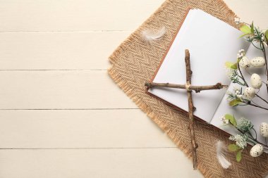 Boş kitaplı haç ve beyaz ahşap arka planda güzel çiçekler. Paskalya kutlaması