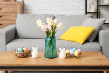 Lale çiçekli ahşap sehpa, Paskalya yumurtaları ve tavşanlar şenlikli oturma odasında, yakın plan.