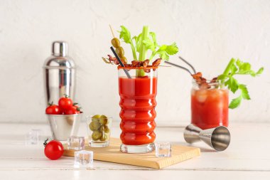 Beyaz arka planda domuz pastırması, kereviz ve zeytinli Bloody Mary kokteyli.