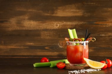 Domuz pastırması, zeytin ve kereviz ile ahşap arka planda bir bardak Bloody Mary kokteyli.