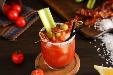 Domuz pastırmalı, zeytinli ve kerevizli bir bardak Bloody Mary kokteyli.