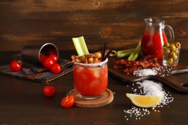 Domuz pastırması, zeytin ve kereviz ile ahşap arka planda bir bardak Bloody Mary kokteyli.