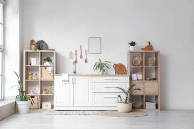 Beyaz tezgahlı, çatal bıçaklı ve raflı şık mutfak.