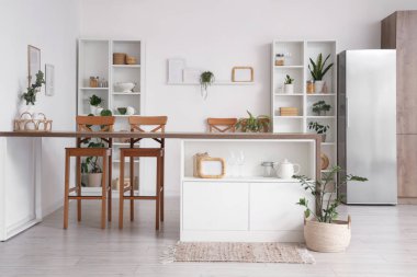 Ada masası, buzdolabı ve raf üniteleri olan şık bir mutfak.