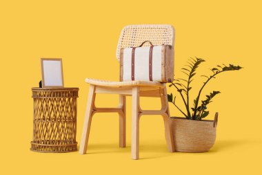 Klasik valizli şık sandalye, sehpa ve sarı arka planda ev bitkisi.