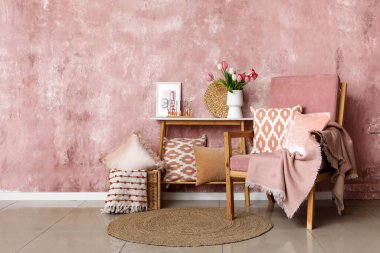 Şık oturma odasının içinde koltuk, masa ve çiçek vazosu var.