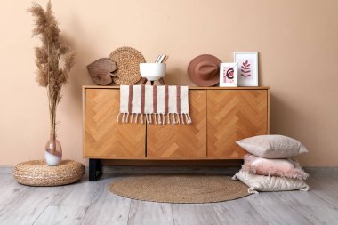 Pembe yastıklı şık bir oda, vazoda kuru çiçekler ve bej duvarın yanında klozet dekoru.