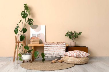 Ev çiçekleri ve bej duvarın yanındaki ahşap bankta pembe desenli şık bir oda.