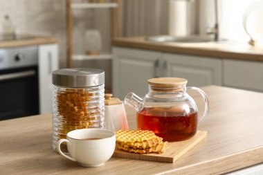 Mutfaktaki masada bir kavanoz waffle ve fincanla çaydanlık.