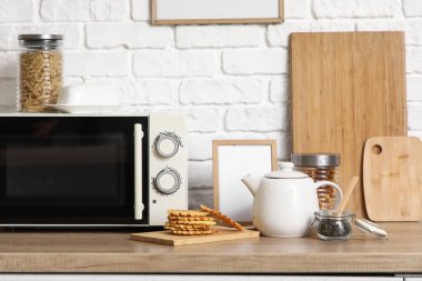 Mutfaktaki masada mikrodalga fırının yanında lezzetli waffle yapan çaydanlık.