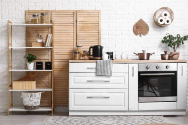 Mutfağın içinde elektrikli su ısıtıcısı, bardak ve bir kavanoz şeker var.