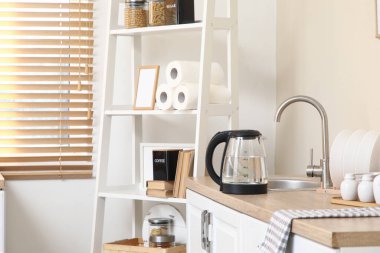 Mutfaktaki lavabonun yanında suyu olan elektrikli çaydanlık.