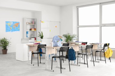 Sıraları ve sırt çantaları olan sınıfın içi.