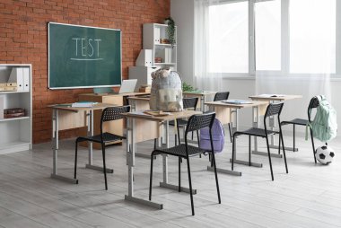 Sıraları, sırt çantaları ve tahtası olan sınıfın içi.